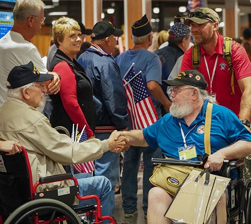 Wels team members assist two veterans who are greeting each other with smiles